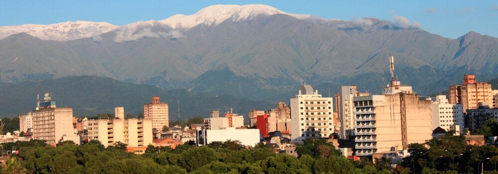 Vista panorámica de Montevideo con montañas en el fondo y edificios en primer plano.