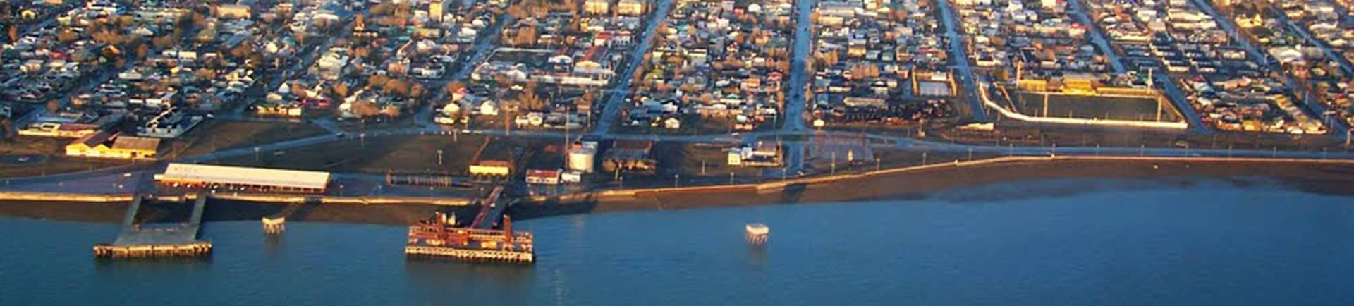 Aerial view of El Kaminante waterfront with boats and city skyline.