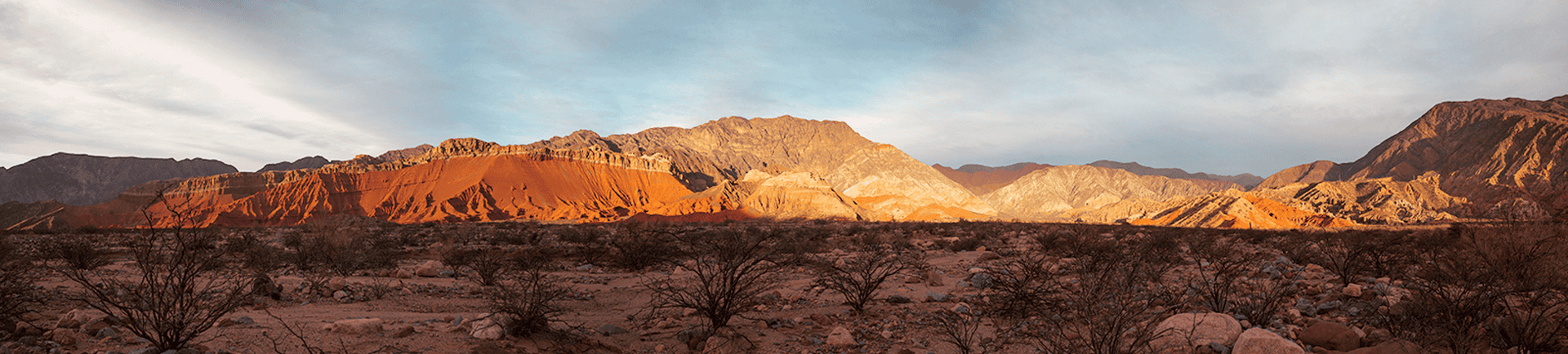 Mountain landscape at sunset with vibrant orange and red hues over rugged terrain.