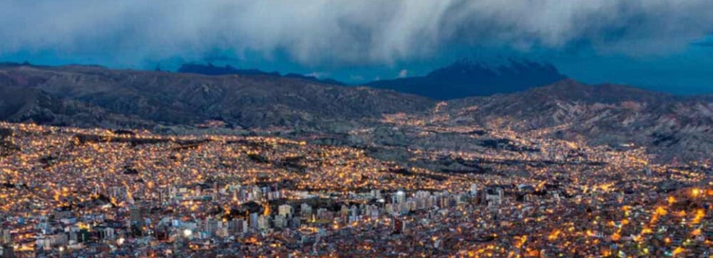 A cozy mountain town illuminated at night with city lights and surrounding hills.