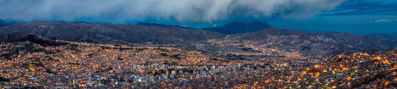 A cozy mountain town illuminated at night with city lights and surrounding hills.