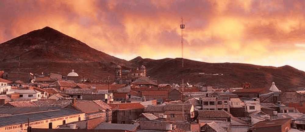 A scenic view of El Kaminante mountain at sunset with a small town in the foreground.