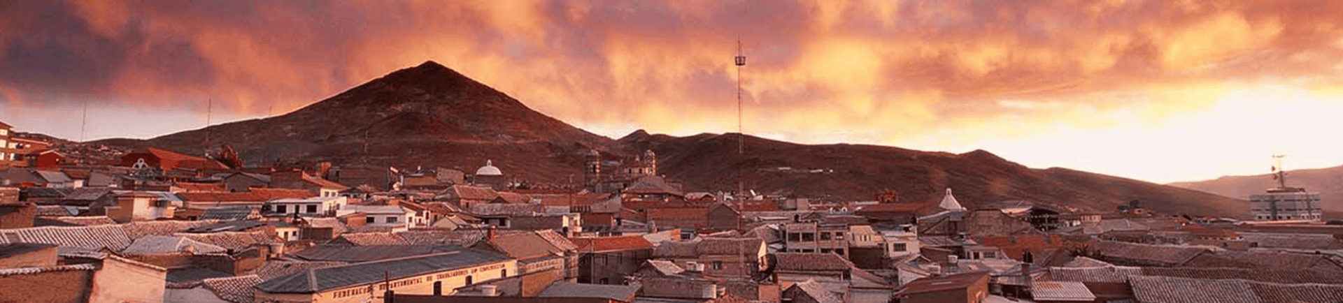 A scenic view of El Kaminante mountain at sunset with a small town in the foreground.