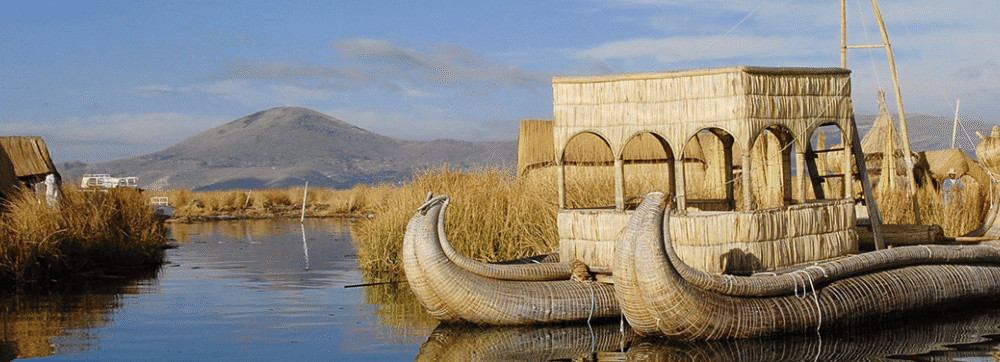 Antiguo barco de pesca en un río con aldeas tradicionales y montañas al fondo.