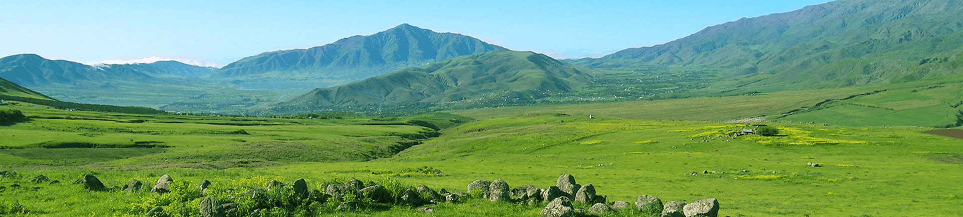 Paisaje de montañas y praderas verdes en un día soleado.