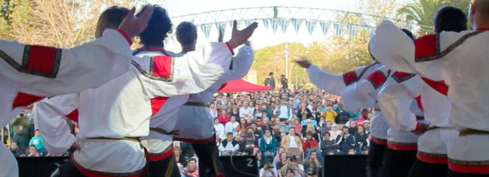 Baile en grupo en una fiesta tradicional al aire libre con música y disfraces coloridos.