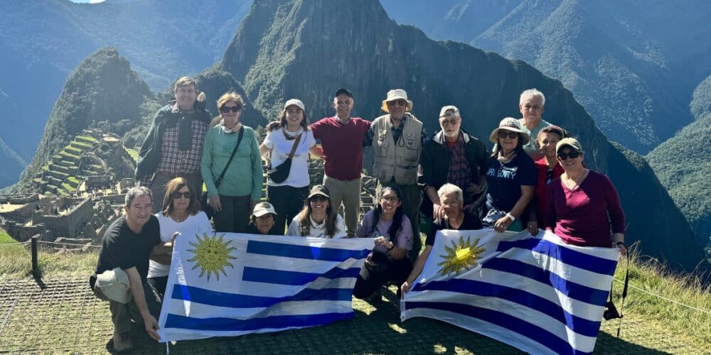 Exploradores con banderas de Uruguay en Machu Picchu, Perú, durante una excursión.