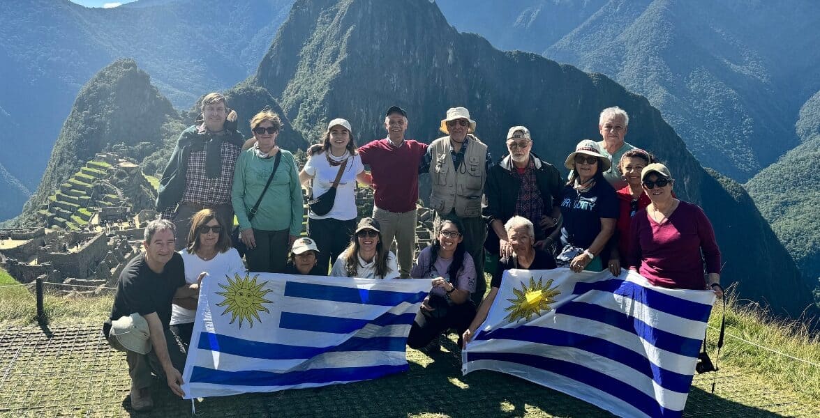 Group of tourists holding Uruguayan flags at Machu Picchu, Peru.