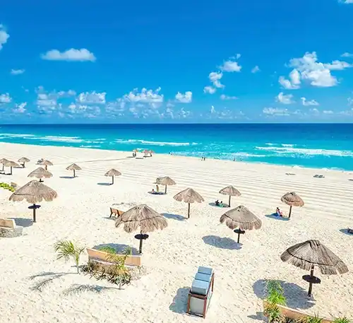 Relaxing beach scene with umbrellas and lounge chairs on white sand under a bright blue sky.
