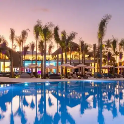 Espectacular vista de un resort con piscina y palmeras al atardecer en El Kaminante, Uruguay.