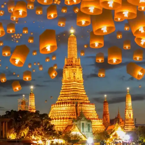 Lámparas flotantes en el cielo sobre un templo en Tailandia al atardecer.