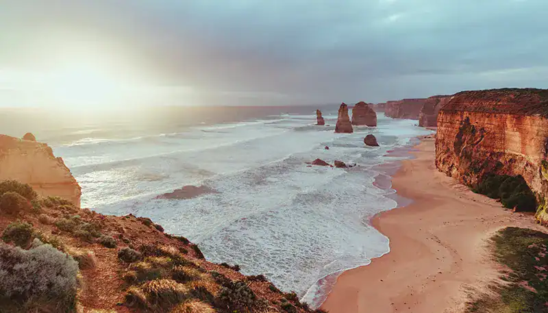 Scenic view of the Algarve coastline with cliffs and rock formations at sunset.
