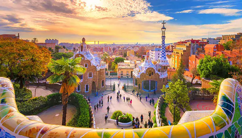 Árboles y edificios en el parque Güell, Barcelona, durante atardecer.