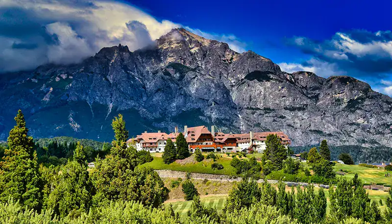 A lush green landscape with a mountain backdrop and a charming village in the foreground.