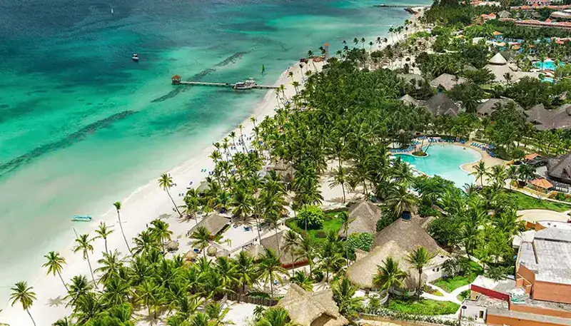 Espectacular vista aérea de una playa tropical con aguas cristalinas y palmeras en un resort de lujo.