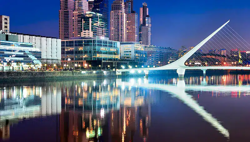 Puente de la Ciudad de Valencia al atardecer, reflejado en el río Túria, en un entorno urbano modern.