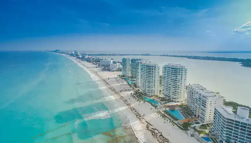 A beachside cityscape with high-rise buildings along the coast and a river in the background.