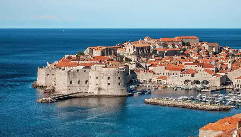 El casco antiguo de Dubrovnik, ciudad costera en Croacia, con murallas y edificios históricos junto.