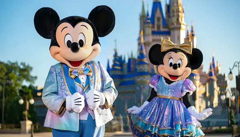 Disfraces de Mickey y Minnie Mouse en Disneyland con castillo de fondo.