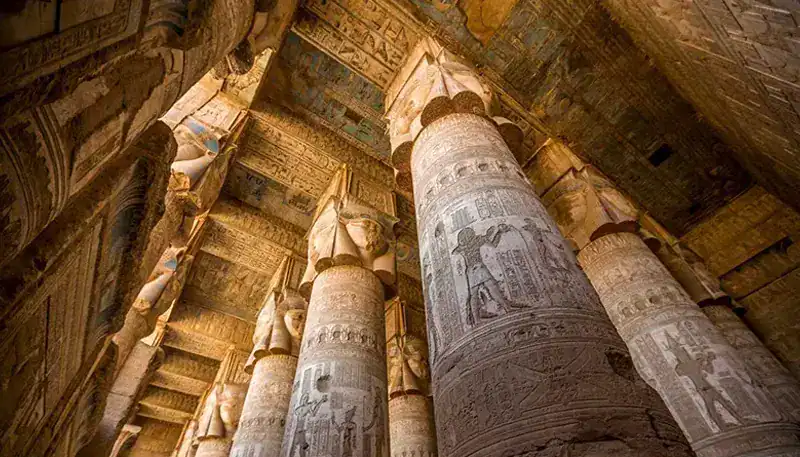 Ancient Egyptian temple columns with hieroglyphic inscriptions and detailed carvings.