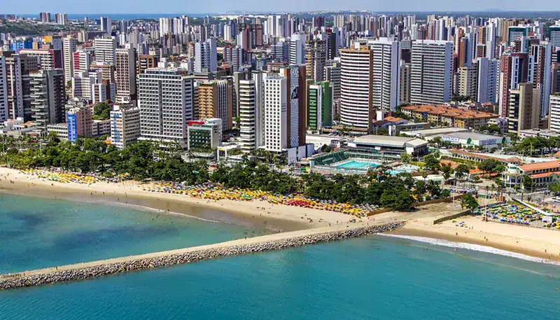 Downtown city skyline with high-rise buildings and a beach in the foreground.