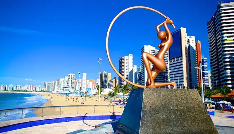 A stunning bronze sculpture of a woman with a hoop, located on a city beach promenade.