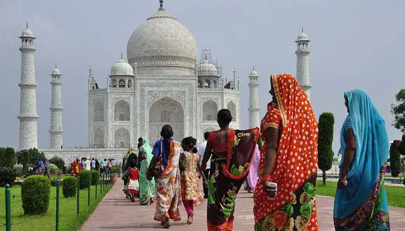 Taj Mahal with visitors in colorful traditional attire, showcasing Indian cultural heritage.