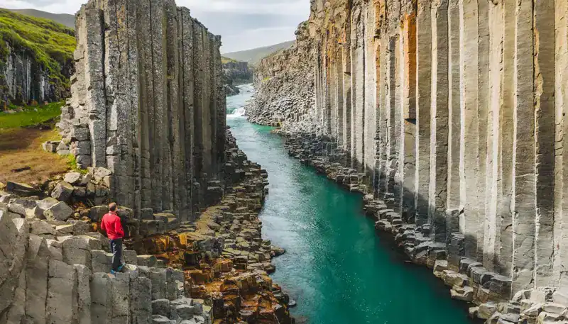 Acantilados de columnas de basalto en Islandia con río en medio, paisaje natural impresionante.