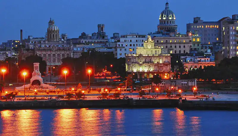 Night view of Havana, Cuba with historic buildings illuminated along the waterfront.