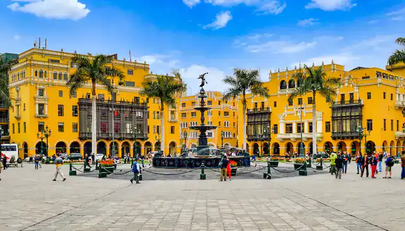 Plaza principal con edificios color amarillo y palmeras en el centro de la ciudad.