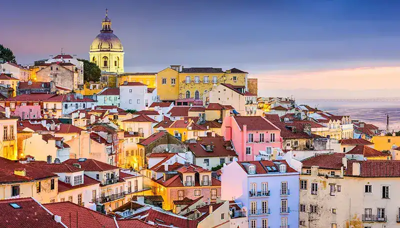 Pintoresco paisaje urbano con casas coloridas y una catedral en el fondo, al atardecer en una ciudad.