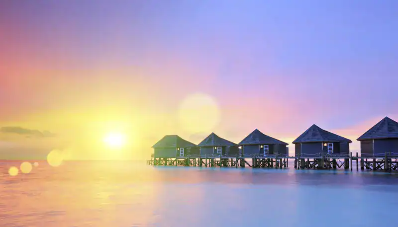 A serene sunset over overwater bungalows in a tropical destination.