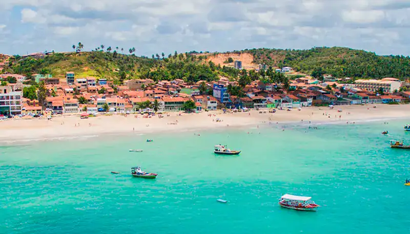 Vista panorámica de una playa con aguas turquesas y embarcaciones en la costa.