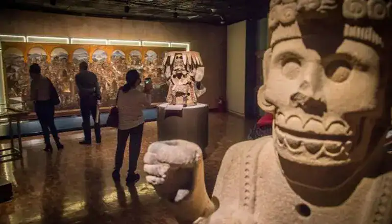 Arte prehispánico en exposición en El Kaminante, Uruguay, con visitantes admirando las piezas arqueo.