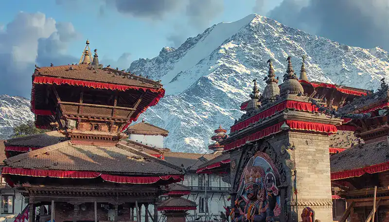 Ancient Nepalese temples with snow-capped mountains in the background.