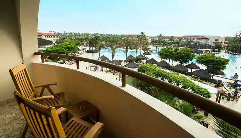 Disfruta de una vista panorámica del resort con piscina y áreas verdes desde el balcón. Ambiente rel.