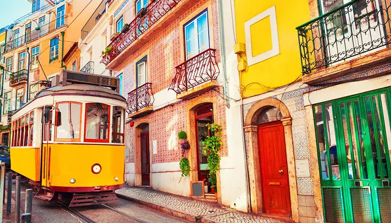 Coche clásico amarillo en calles coloridas de ciudad europea.