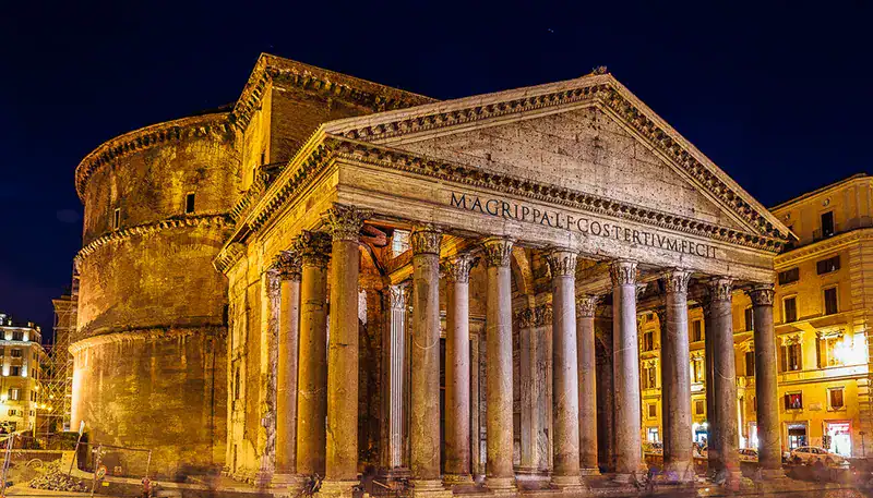 El Kaminante, arquitectura clásica en Roma iluminada de noche.