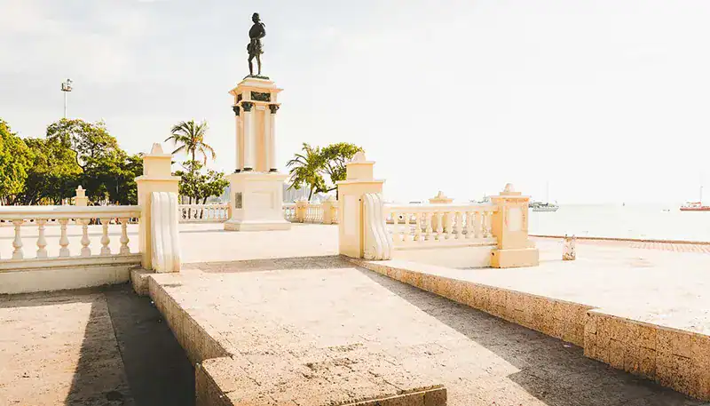 Historic waterfront promenade with statue and palm trees in Montevideo, Uruguay.