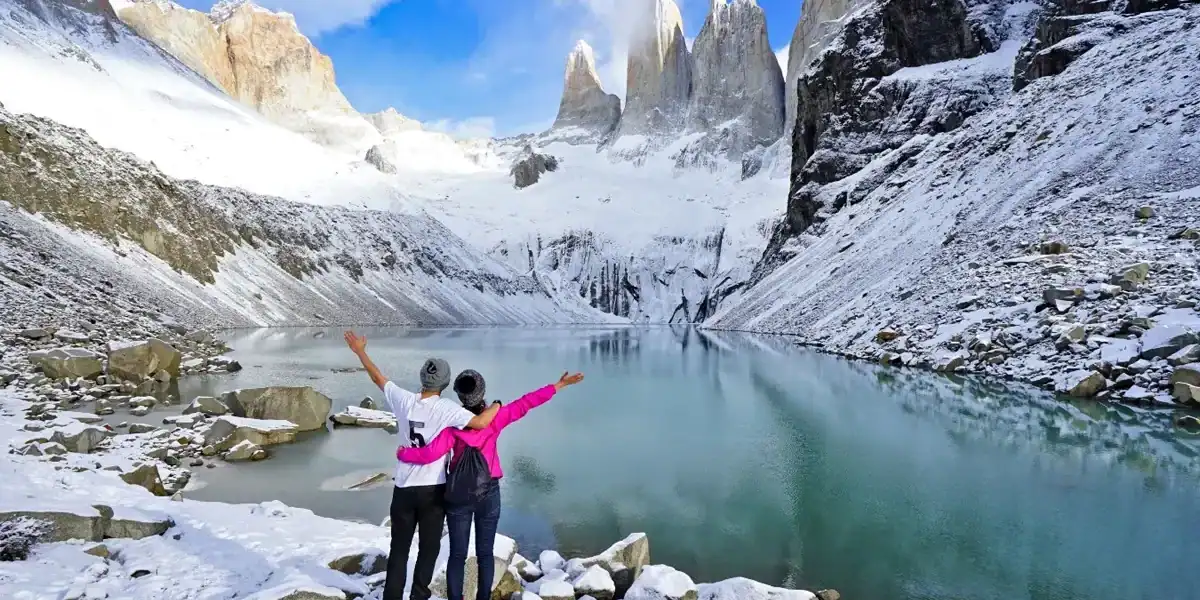 A lush mountain landscape with a glacier-fed lake and snow-covered peaks.