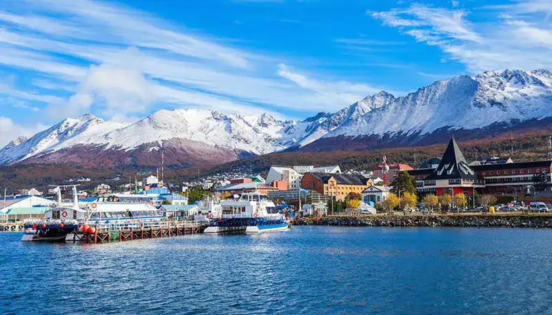 Snow-capped mountains and a vibrant harbor in a scenic coastal town.