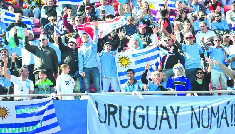 Aficionados uruguayos celebrando con banderas en un estadio.