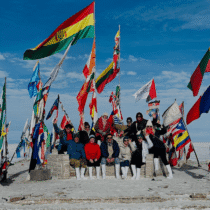 Viento en la playa con banderas de diferentes países y grupo de personas disfrutando del paisaje.