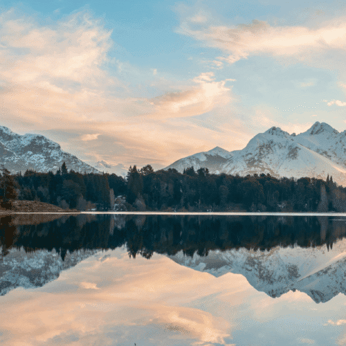 Espectacular vista de montañas nevadas reflejadas en un lago en un atardecer.