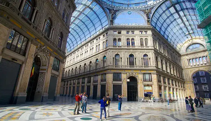 El edificio histórico en un interior de vidrio y mármol, con visitantes admirando la arquitectura.
