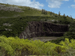 Volcanic crater surrounded by lush green vegetation and hillside landscape.