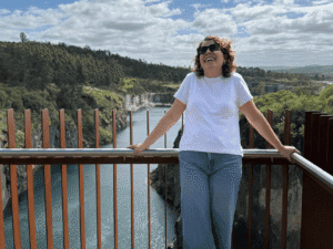 Enjoying the scenic view from a bridge over a river with lush greenery and cliffs in the background.