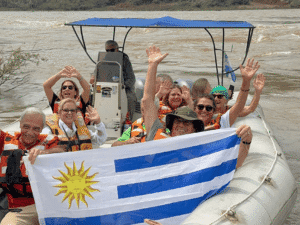 Barco turístico en río con grupo de personas disfrutando del paseo y la naturaleza.