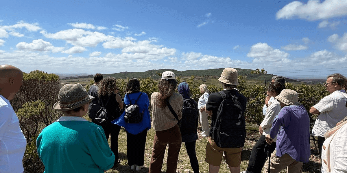 A group of people enjoying a guided outdoor tour in a scenic natural landscape with hills and blue s.