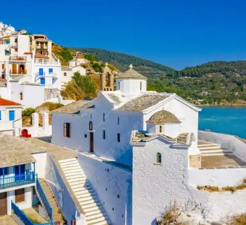 Pueblo costero de casas blancas en Santorini, Grecia, con vista al mar y cielo despejado.